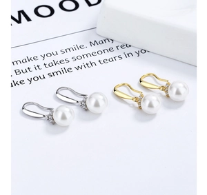 Gros plan de boucles d'oreilles pendantes en perles avec cristaux en or et argent