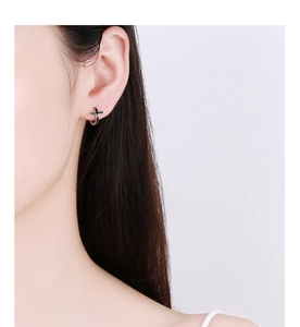Vue latérale de créoles en argent 925 avec croix en émail noir portées par un mannequin