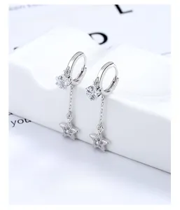 Detail of silver star tassel earrings with zircon stones on white display stand