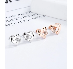 Détail des boucles d'oreilles cœur en argent et or rose avec cristaux étincelants