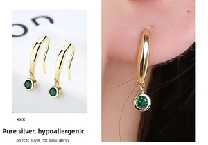 Close-up of 925 sterling silver emerald earrings with green stones and hypoallergenic gold hooks