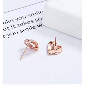 Gros plan du poinçon S925 sur des boucles d'oreilles cœur en or rose au design ajouré