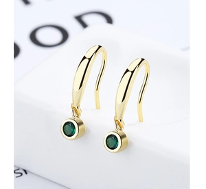 Macro shot of 925 sterling silver gold earrings with emerald green gemstones