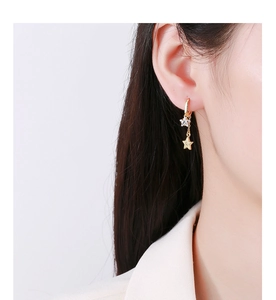 Close-up of golden star tassel earrings with white zircon on a model for a luxury look
