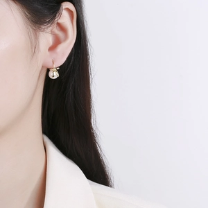 Elegant gold bow earrings with teardrop pearls on model for a classic French style