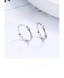 Gros plan de créoles Mobius en argent avec strass scintillants sur une surface blanche