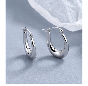Macro shot of chunky silver hoop earrings with a mirror polished finish on blue background
