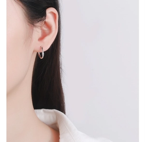 Gros plan d'une boucle d'oreille Mobius en argent avec zircons portée sur l'oreille d'un modèle