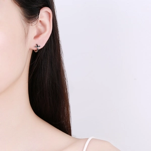 Boucles d'oreilles créoles croix en argent noir portées par un mannequin pour le style
