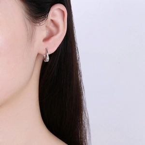 Elegante silberne Bogenohrringe mit Zirkonia-Mikrofassung am Ohr eines Models