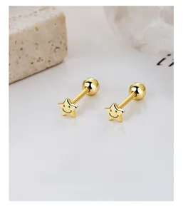 Detail of gold star screw-back studs featuring a smiling face engraved on polished metal