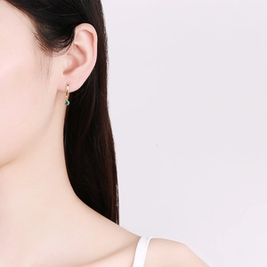 Elegance 925 sterling silver gold earrings featuring emerald green round gemstones on model