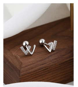 Macro detail of silver W-letter stud earrings with pavé crystals and secure screw backs
