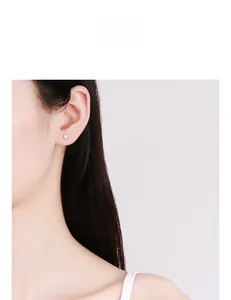 Close-up of a minimalist star stud earring worn on ear to show size and geometric style