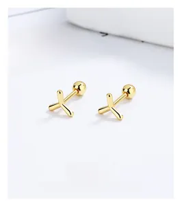 Macro detail of gold pinwheel screw earrings with ball back closures on minimalist paper