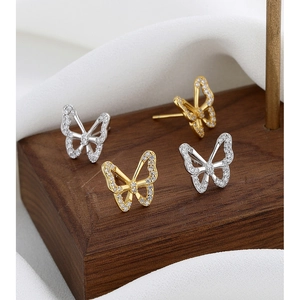 Macro shot of 925 silver and gold butterfly stud earrings with zircon stones