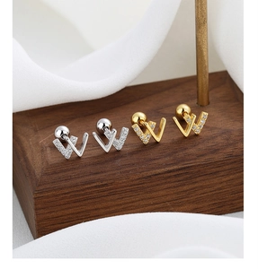Macro detail of silver and gold letter W screw back earrings with crystal accents
