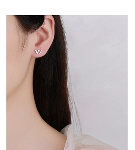 Close-up of a 925 sterling silver W-letter stud earring with zircon inlay on a model