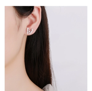 Close-up of a delicate silver butterfly stud earring with shimmering crystal inlay