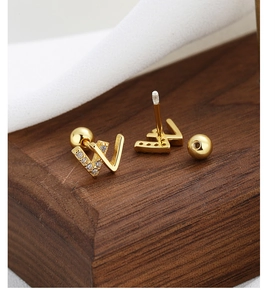Detailed macro view of gold letter W screw back earrings with white cubic zirconia stones