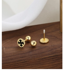 Macro detail of gold cross earrings with black enamel inlay and screw back closure