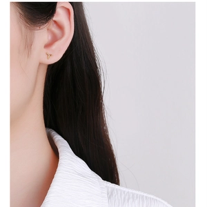 Macro shot of minimalist gold geometric screw-back stud earring worn on the earlobe