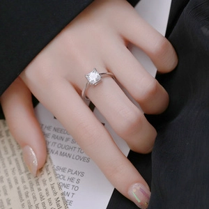 Detail of square princess cut moissanite ring with four-prong silver setting on hand