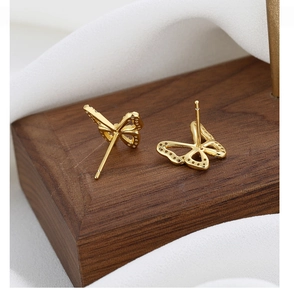 Macro view showing side detail of gold butterfly earrings with micro-inlaid crystals