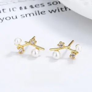 Vue macro de boucles d'oreilles en forme de branche dorée avec perles et zircons brillants