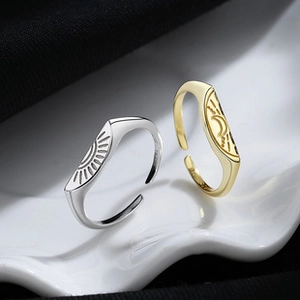 Detail of adjustable silver and gold sun and moon rings on a white textured plate
