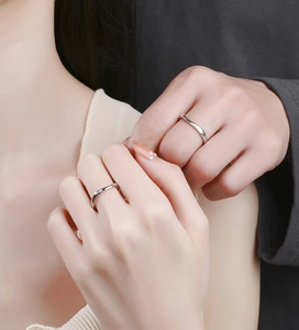 Dettaglio di anelli di coppia in argento 925 ondulati con un piccolo diamante sulle mani