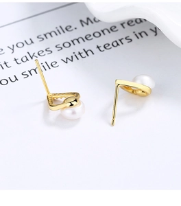 Vue macro de boucles d'oreilles perles dorées en V avec micro-diamants scintillants