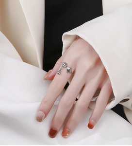 Detailed view of retro silver lotus koi ring with bell charm on model finger