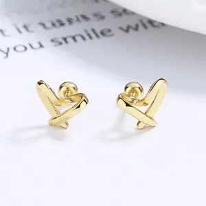 Close-up of golden hollow heart earrings with secure screw-back ball closure design