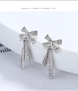 Detailed close-up of 925 sterling silver bow earrings with long tassels and zircon stones