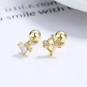 Detailed close-up of asymmetrical gold heart and arrow earrings with zirconia stones