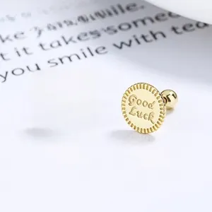Detailed macro view of gold circular earrings with Good Luck engraving and screw back