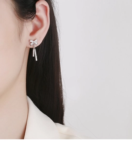 Detailed close-up of silver bow tassel earrings with sparkling white cubic zirconia