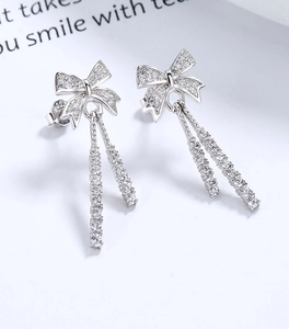 Macro shot of 925 sterling silver bow earrings with sparkling zirconia and long tassels