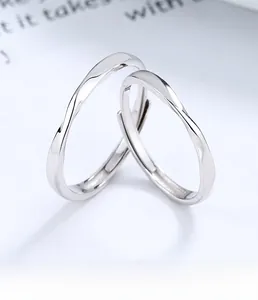 Anelli di coppia Möbius in argento lucido con design a onde intrecciate su carta bianca