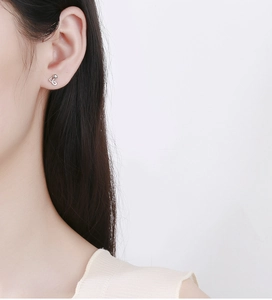 Detail of music note S925 sterling silver earring worn on model ear with white background