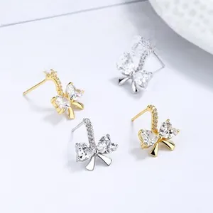 Detail of silver bowknot stud earrings with heart-shaped zircon and pavé crystals