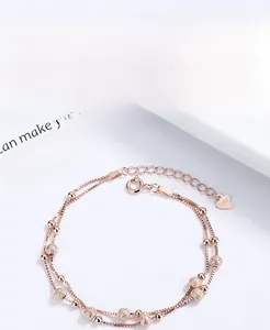 Macro shot of 925 silver double-layer rose gold bracelet with heart charm and beads