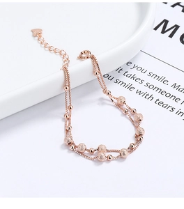 Detail of rose gold double-layer bead bracelet with matte and polished beads and heart tag