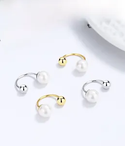Macro shot of 925 silver C-shape earrings with pearls and metal beads in gold and silver