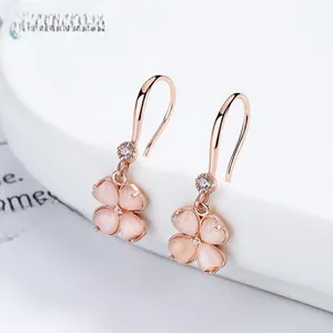 Vue macro de boucles d'oreilles trèfle en or rose avec pétales roses et zircons brillants