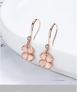 Gros plan de boucles d'oreilles trèfle en or rose avec pierres œil de chat et zircons