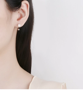 Detail view of double-sided 925 silver C-shape earring with pearl and metal ball on ear