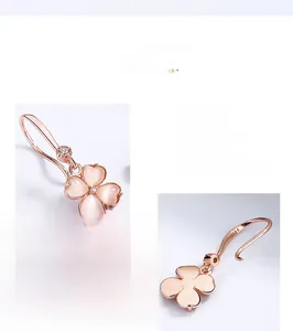 Détails macro des boucles d'oreilles trèfle en or rose avec pétales en opale rose et S925