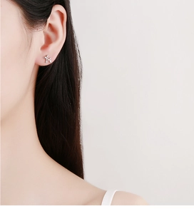 Detail shot of a silver balloon dog earring worn on a model's earlobe in a modern style